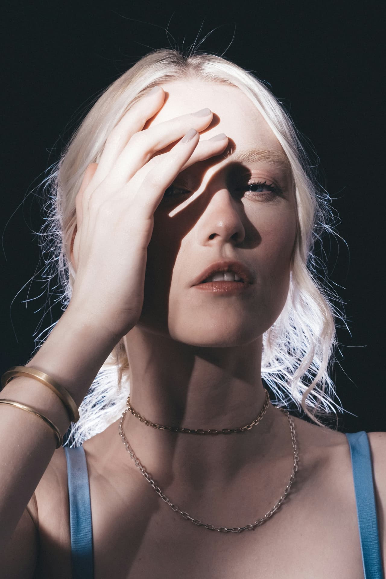 Layered gold necklaces and bangles in a sunlit portrait